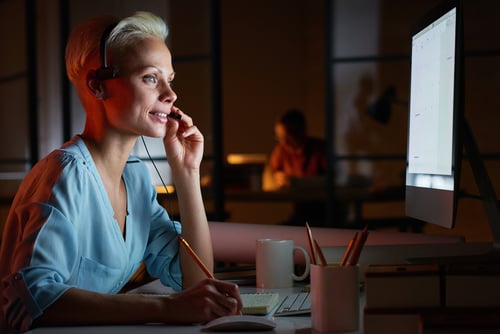 Young woman in headphones working on computer while sitting at her workplace Young woman in headphones working on computer while sitting at her workplace